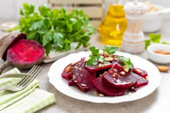 Rote Beete auf einem weißen Teller, daneben Olivenöl und Gemüse
