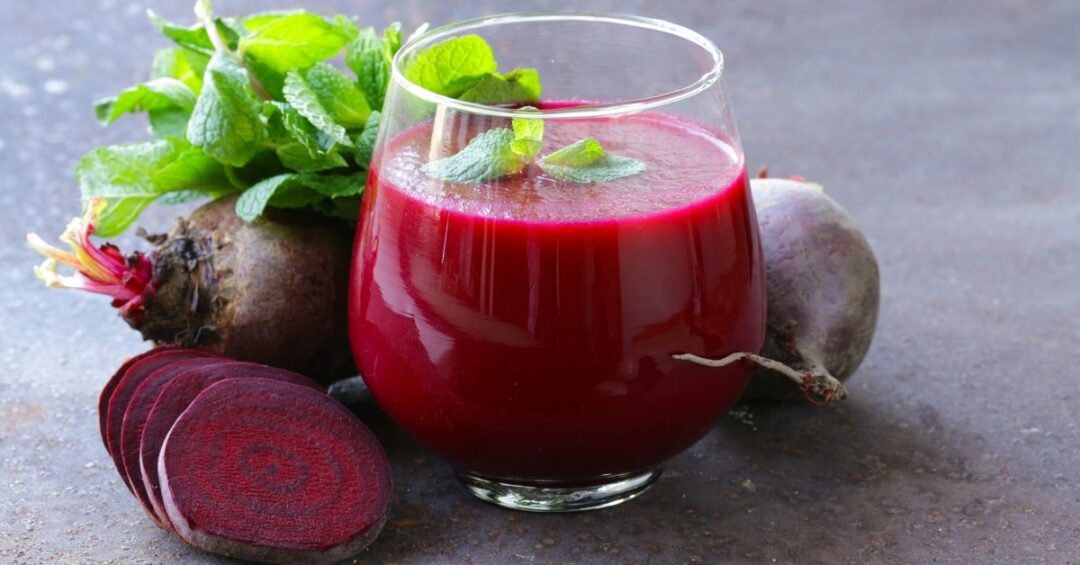 Glas mit Rote-Bete-Saft, frischer Roter Bete und Minze als natürliche Ergänzung einer Ernährung für Blutzucker, Cholesterin und Gefäßgesundheit.
